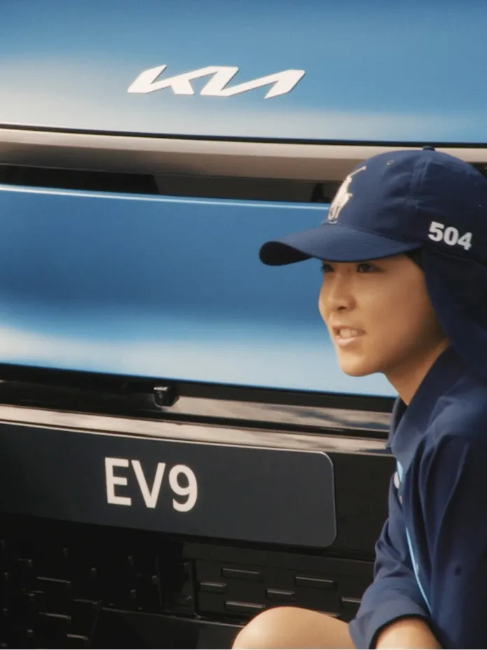Child of a Kia vehicle owner participating as a ball kid beside a Kia EV9