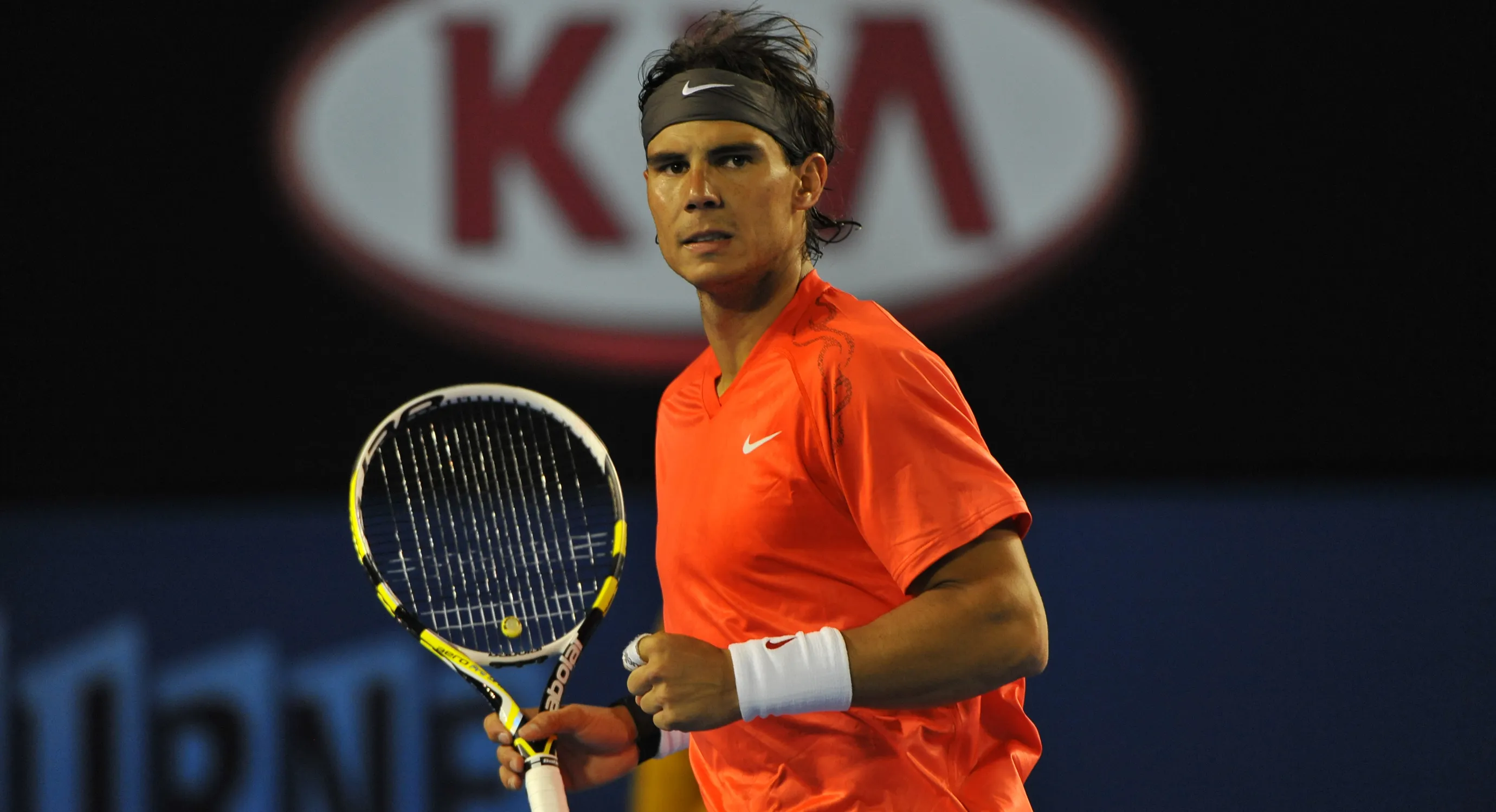 Rafael Nadal holding a racket and looking toward the court.