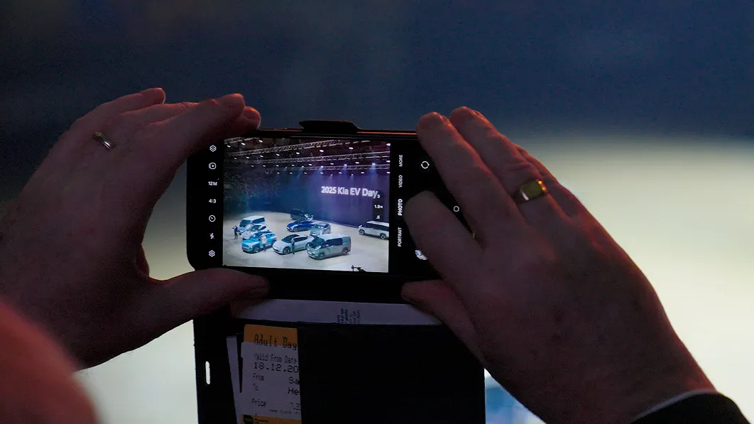 Visitor photographing vehicles at the EV Day exhibition with a smartphone