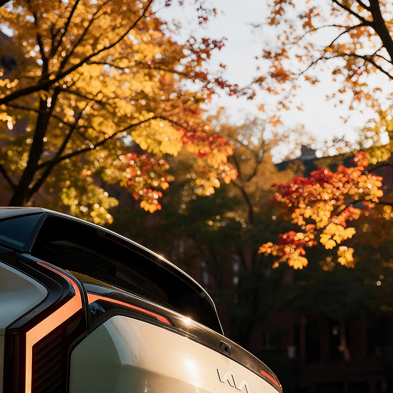 The Kia EV3 side view against autumn foliage