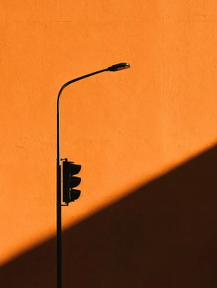 A street lamp casting shadows on an orange wall