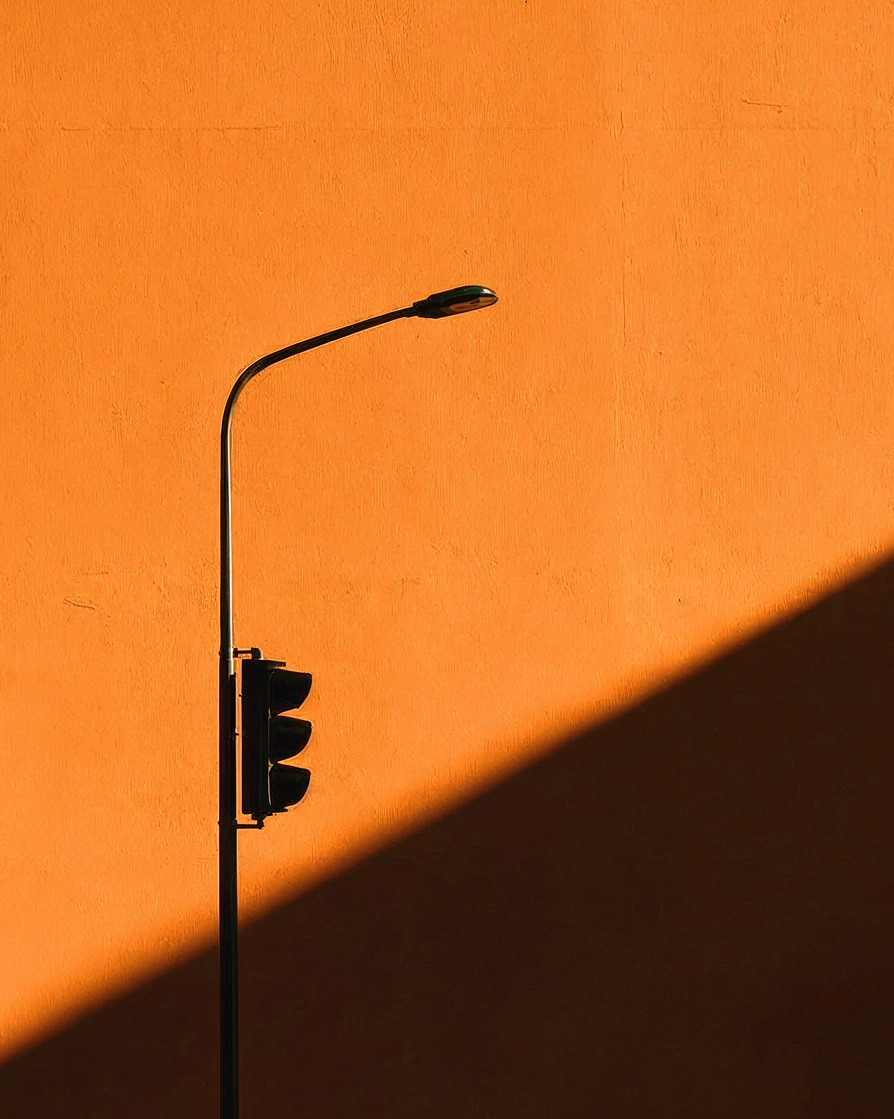 A street lamp casting shadows on an orange wall