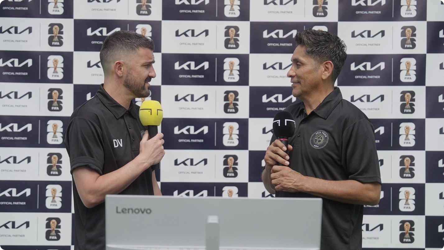 Coaching staff conducting an interview with microphones in front of a Kia Official Partner backdrop