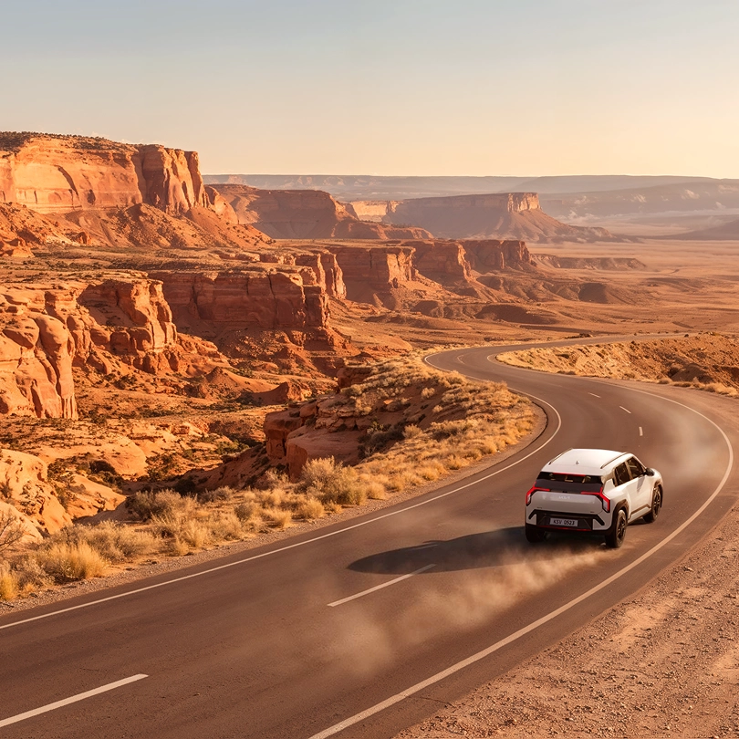 Kia EV3 driving along a winding road through an orange canyon