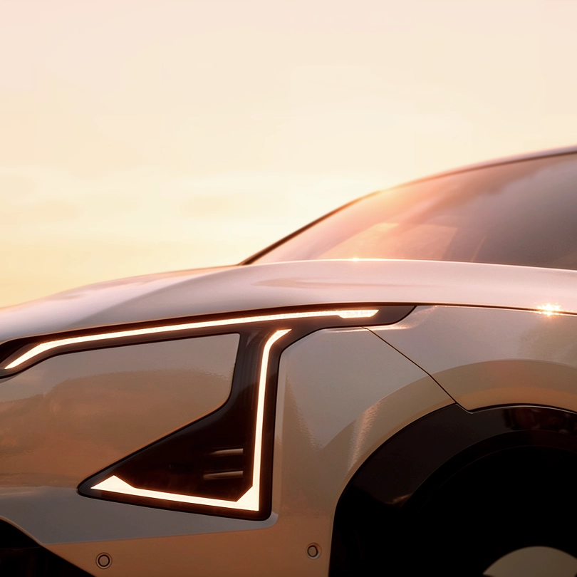 Image of the side view of a Kia EV9 parked on a coastal road at sunset.
