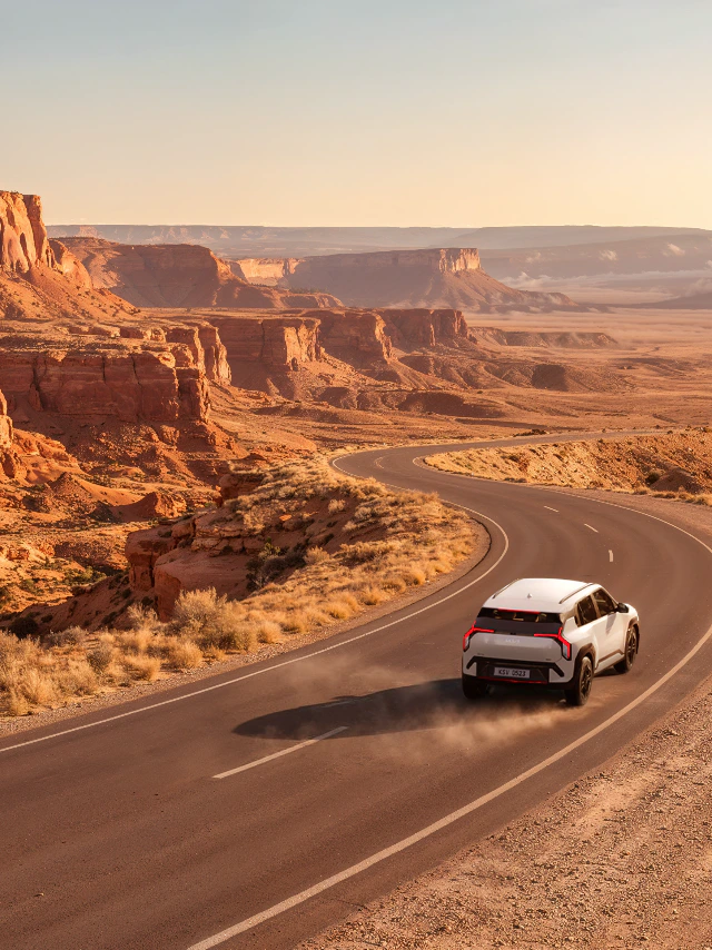 Kia EV3 driving along a winding road through an orange canyon