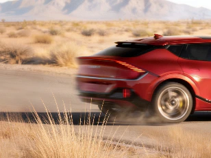 Image of the rear view of a red Kia EV6 GT driving at high speed on a desert road.