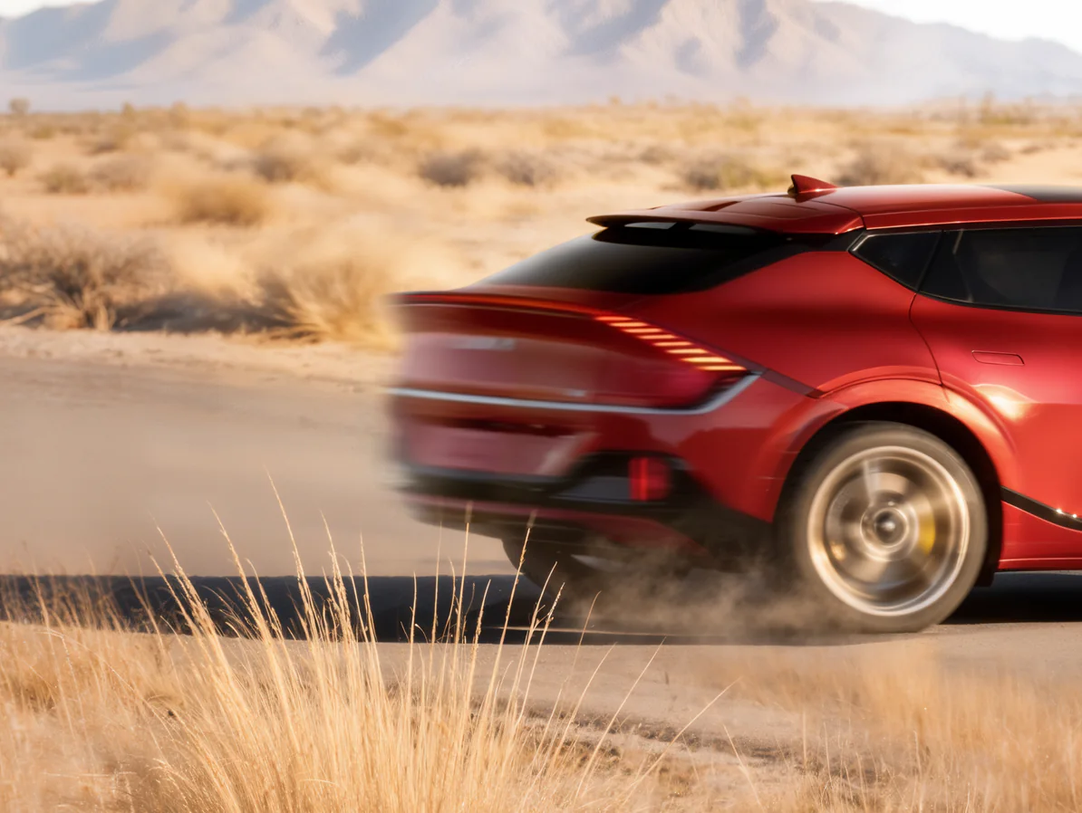 Image of the rear view of a red Kia EV6 GT driving at high speed on a desert road.
