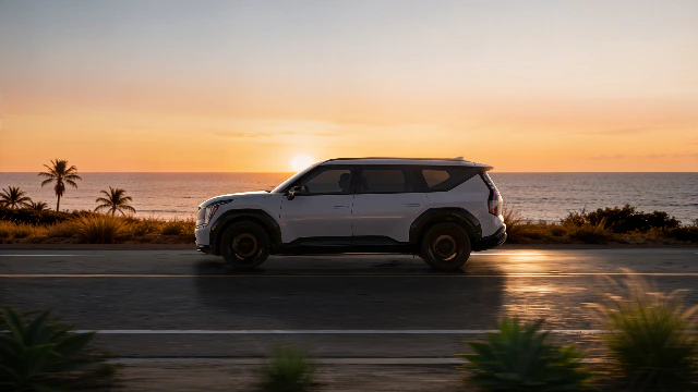 Kia SUV driving along a coastal road at sunset