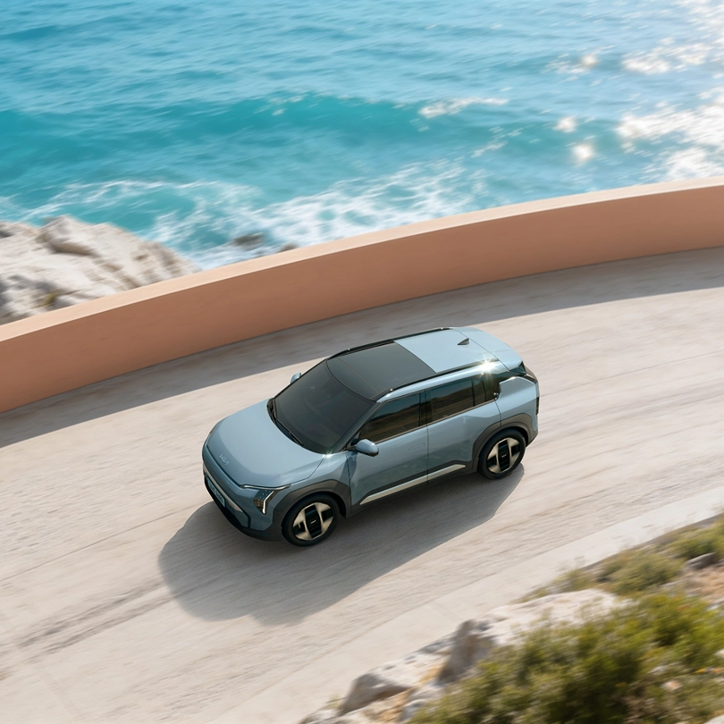 Side view image of the Kia EV5 driving along a coastal road