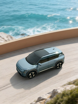 Side view image of the Kia EV5 driving along a coastal road