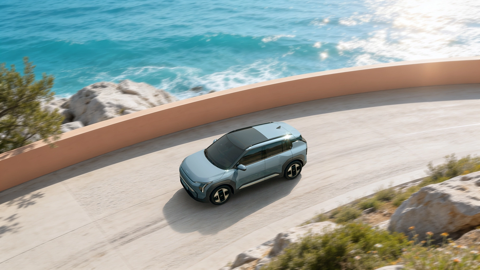 Side view image of the Kia EV5 driving along a coastal road
