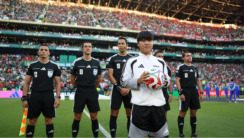 Ball kid entering the stadium holding a football while wearing a Kia-branded uniform