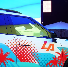 A close-up of the side of a Kia vehicle wrapped with LA logo and palm tree graphics
