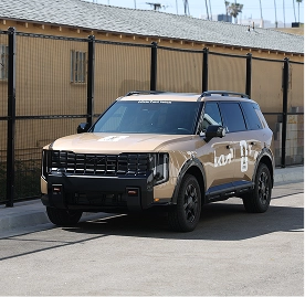 A beige Kia Telluride with branded livery parked on an outdoor road