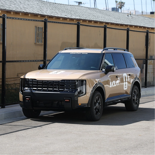 A beige Kia Telluride with branded livery parked on an outdoor road