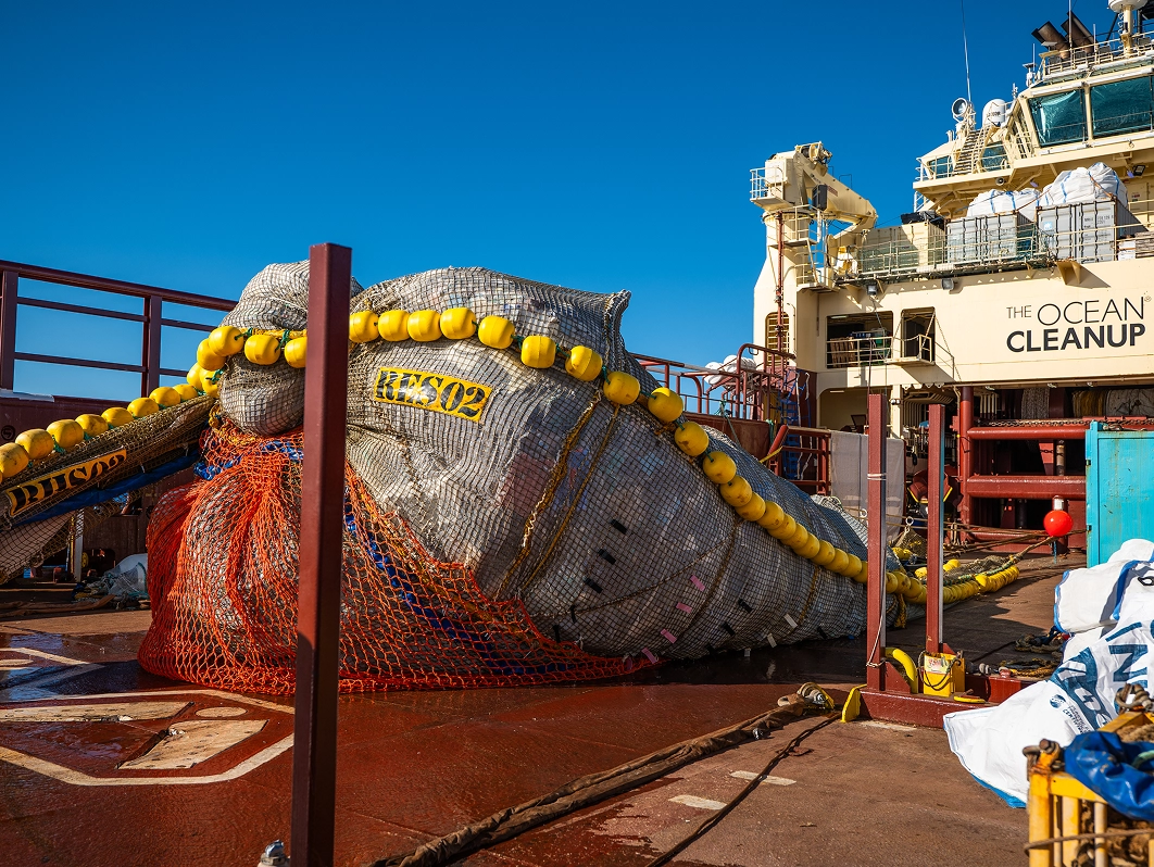 Large marine waste collection nets and buoy equipment loaded on a ship deck at sea