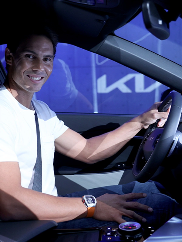 Rafael Nadal seated inside a Kia vehicle holding the steering wheel