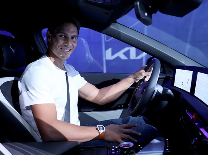 Rafael Nadal seated inside a Kia vehicle holding the steering wheel