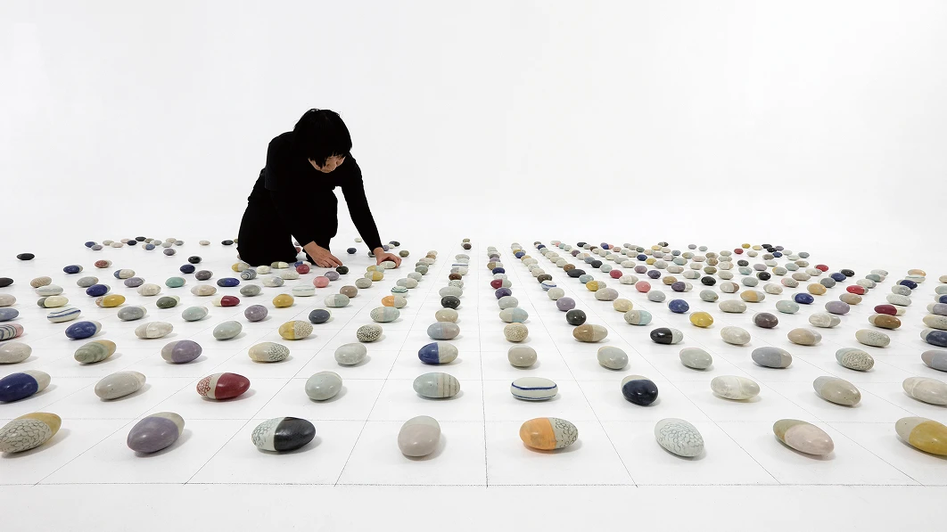 Image of a person arranging various ceramic objects placed on the floor
