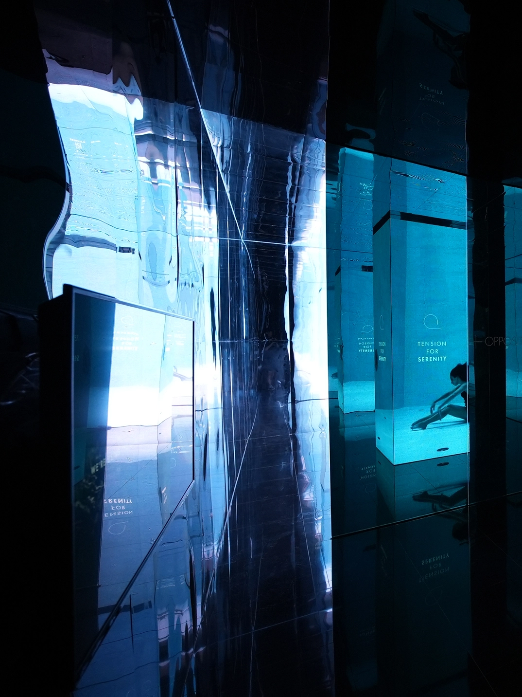 Exhibition space with blue-toned transparent panels and layered mirror reflections at the Gwangju Design Biennale.