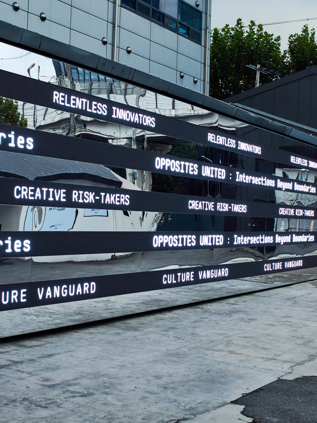 Media strips along the building exterior displaying repeated 'OPPOSITES UNITED' typography at the Seongsu solo exhibition in Seoul.