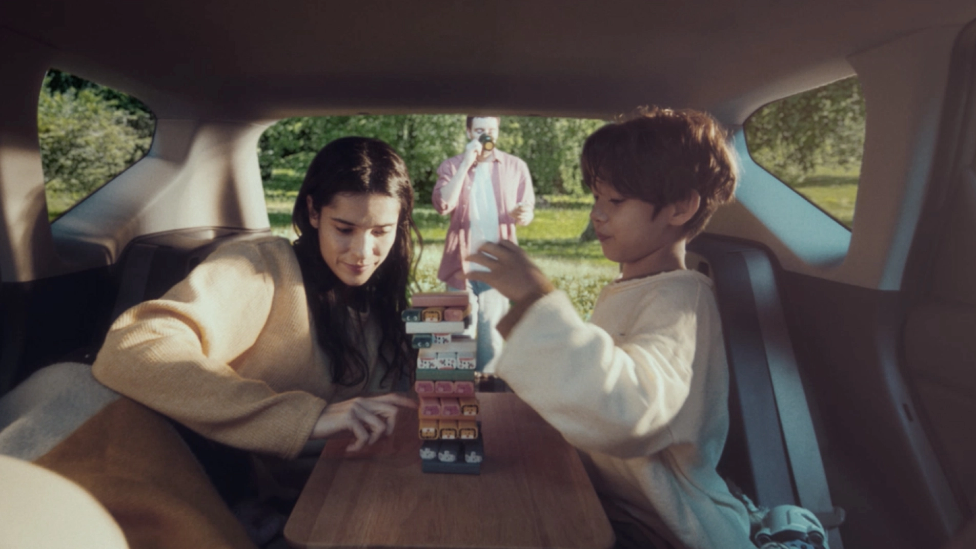 Mother and child playing a board game inside the EV5 with the 2nd-row folded.