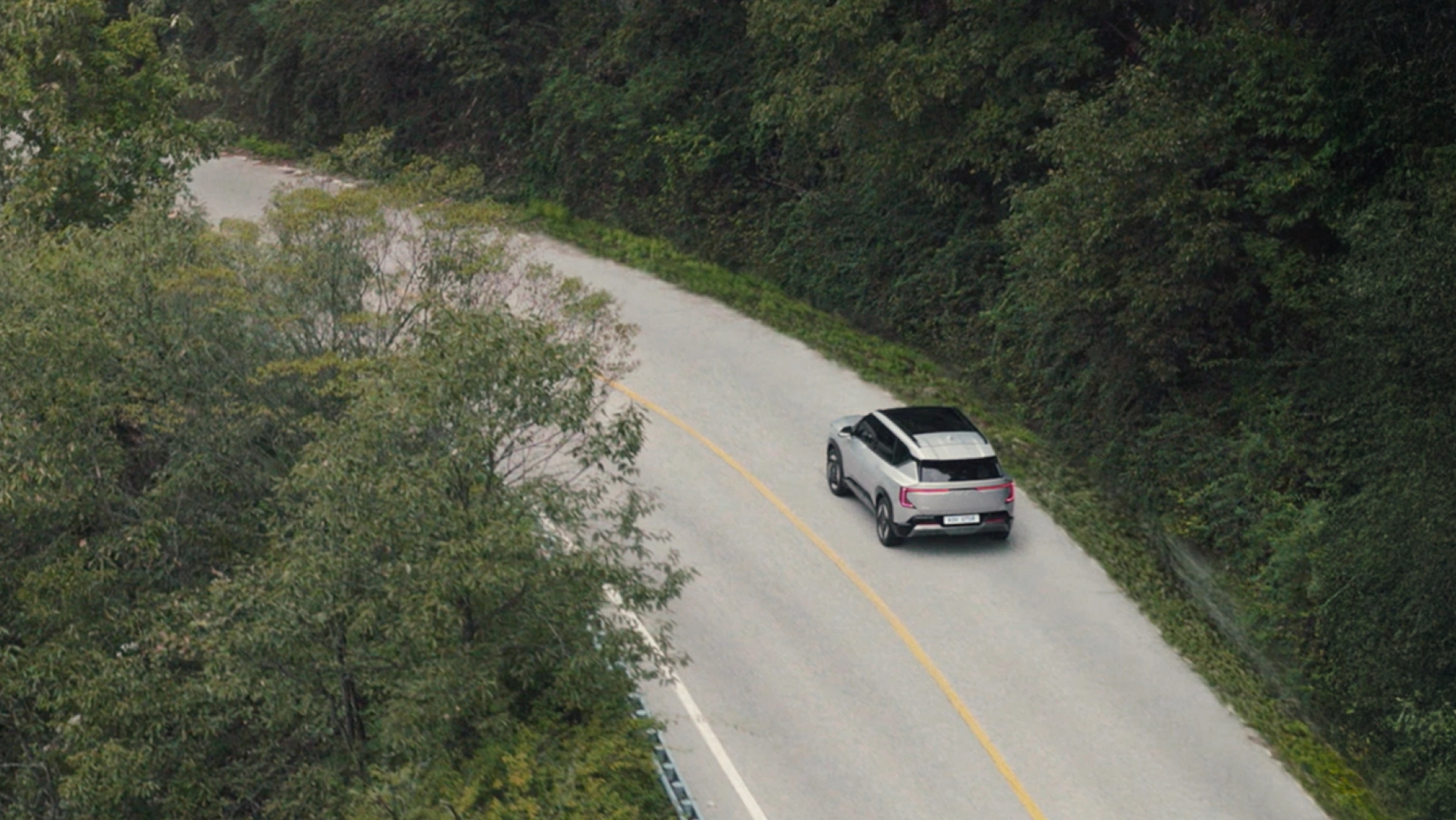 The EV5 driving on a paved road through the forest