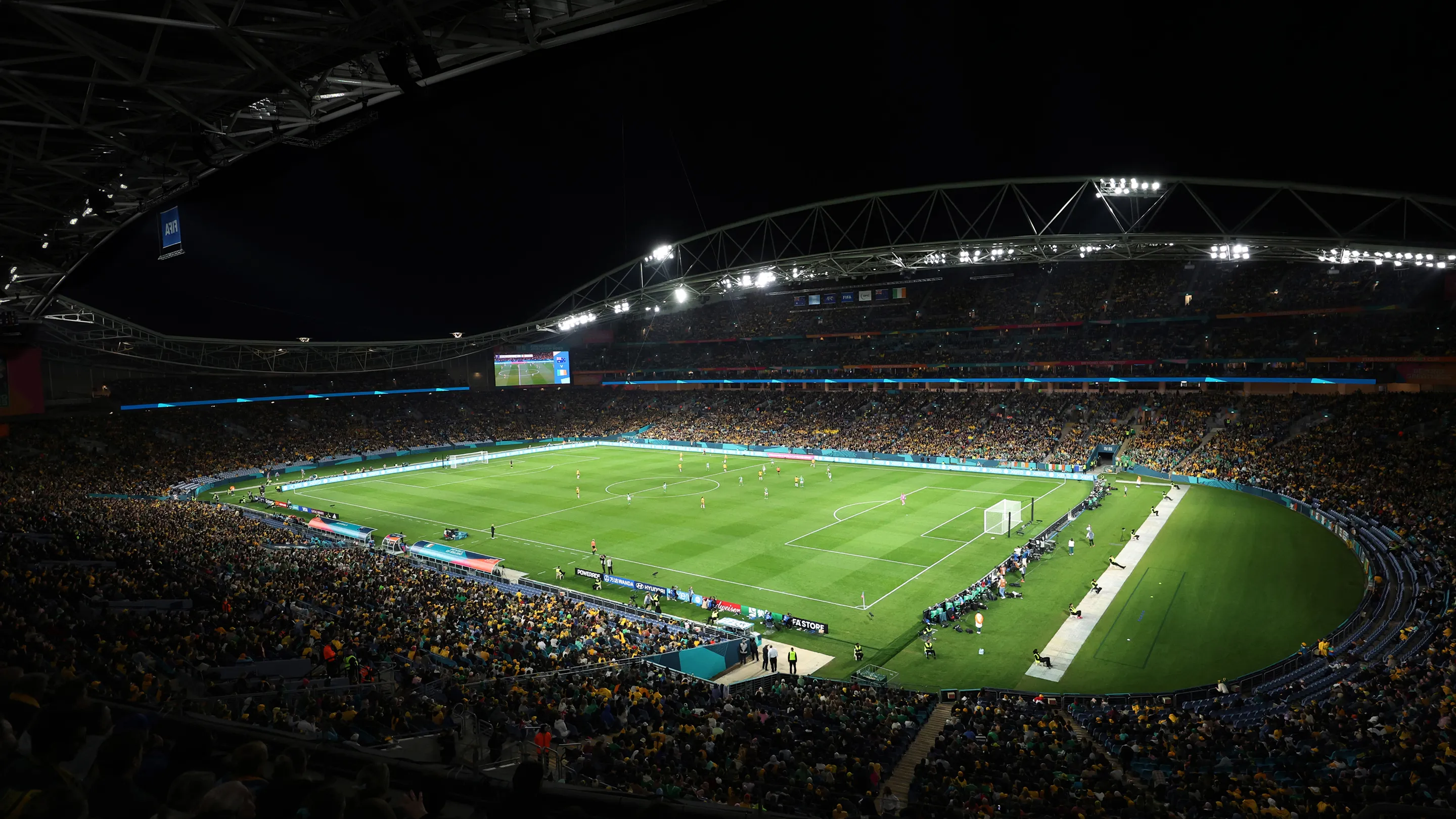 Panoramic view of a football stadium under night lights filled with spectators