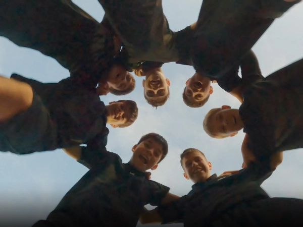 Image of youth players forming a circle with hands together before delivering the official match ball
