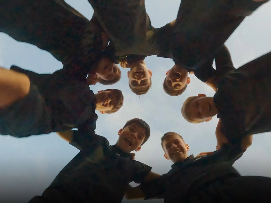 Image of youth players forming a circle with hands together before delivering the official match ball