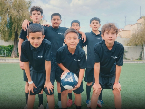 Image of youth players holding the official match ball on the football field