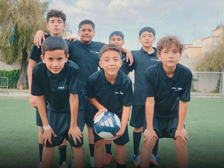 Image of youth players holding the official match ball on the football field