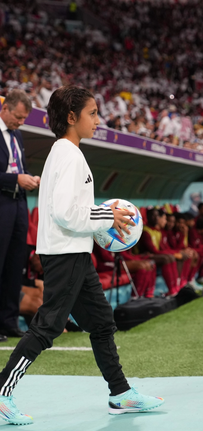 Image of a youth player entering the FIFA stadium carrying the official match ball