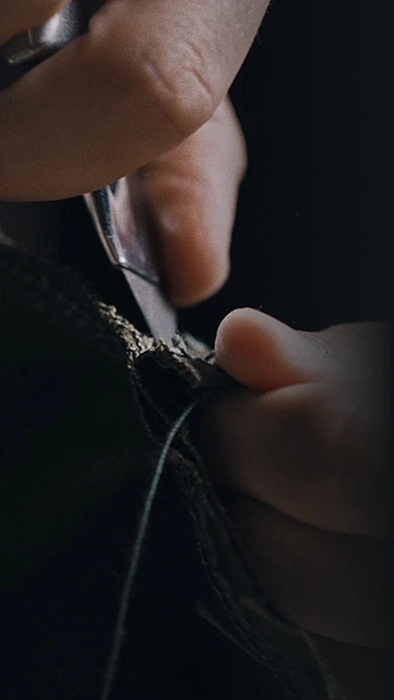 Close-up of hands cutting fabric fibers with scissors