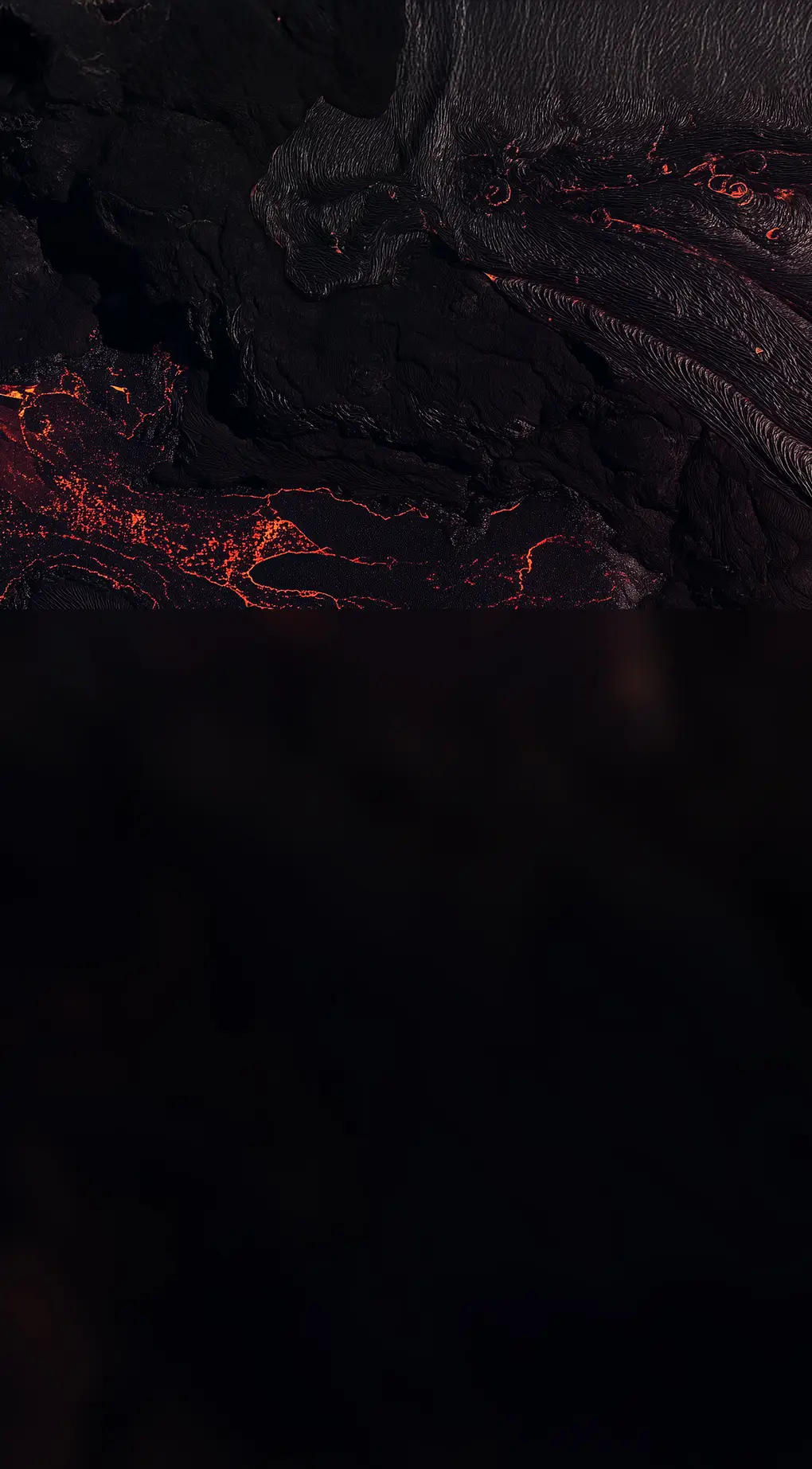 Close-up of red lava flowing over dark volcanic terrain.