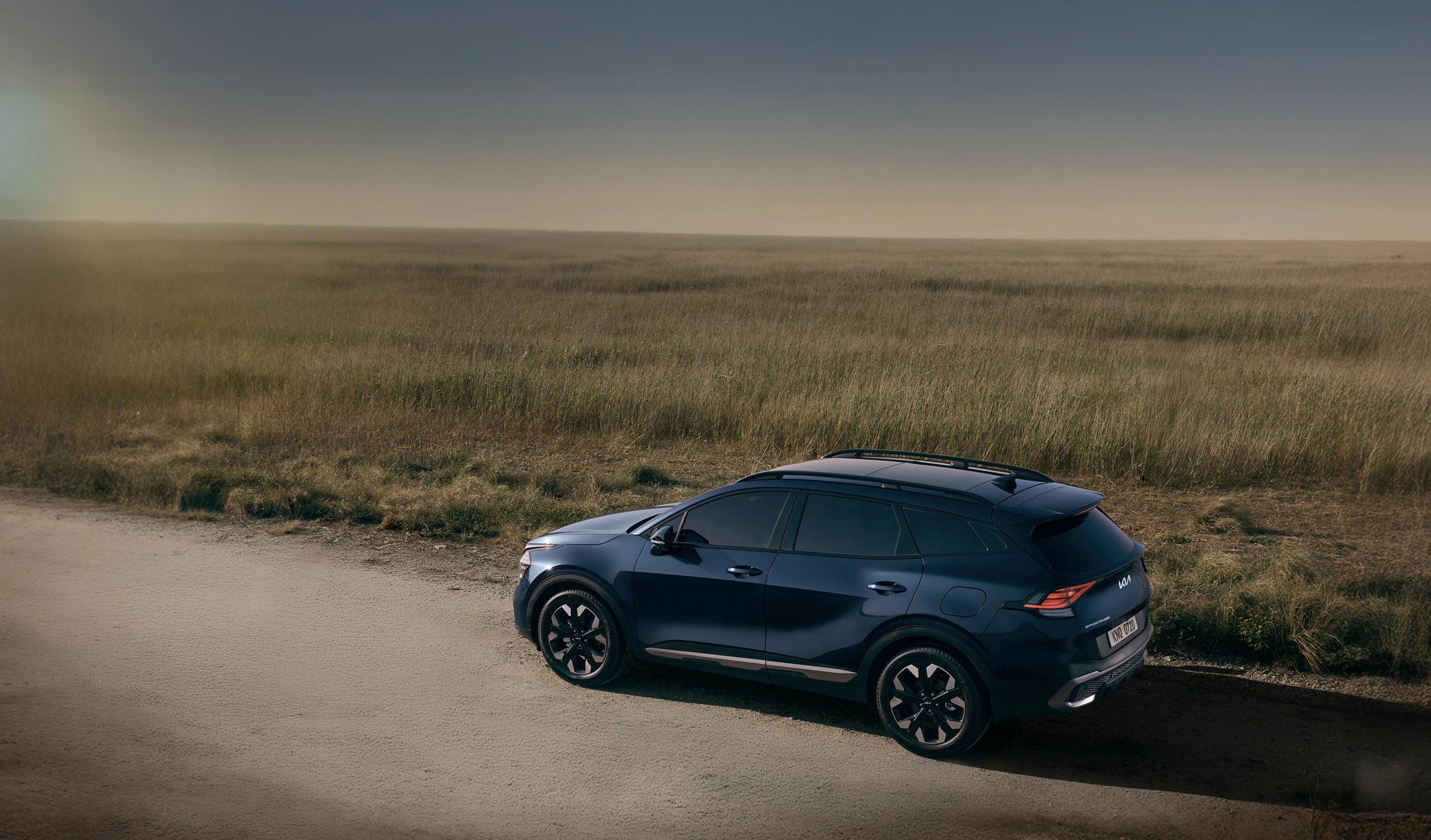 The fourth-generation Kia Sportage driving on a road with reeds