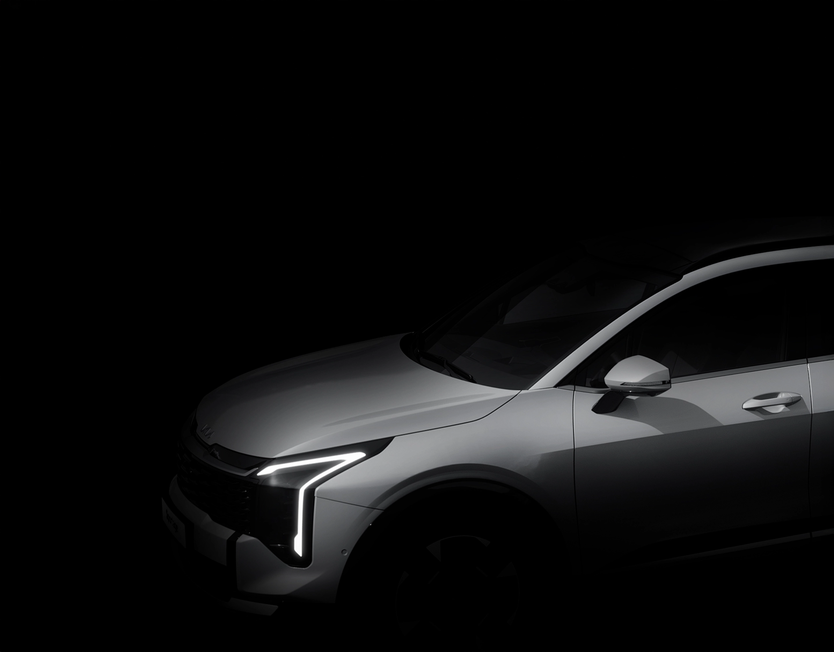 Black-and-white image of the Kia Sportage with headlights illuminated in the dark