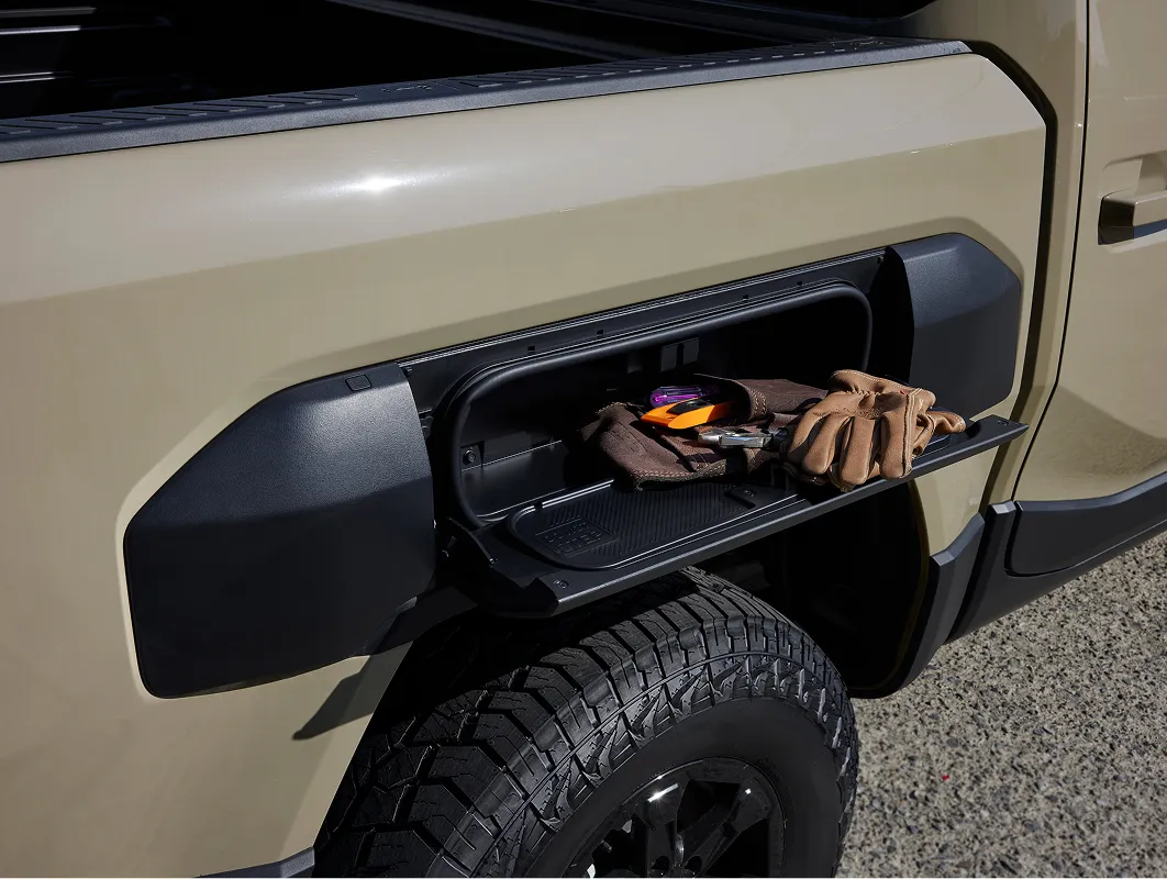 Close-up view of the exterior storage compartment integrated into the front fender of the Kia Tasman pickup truck