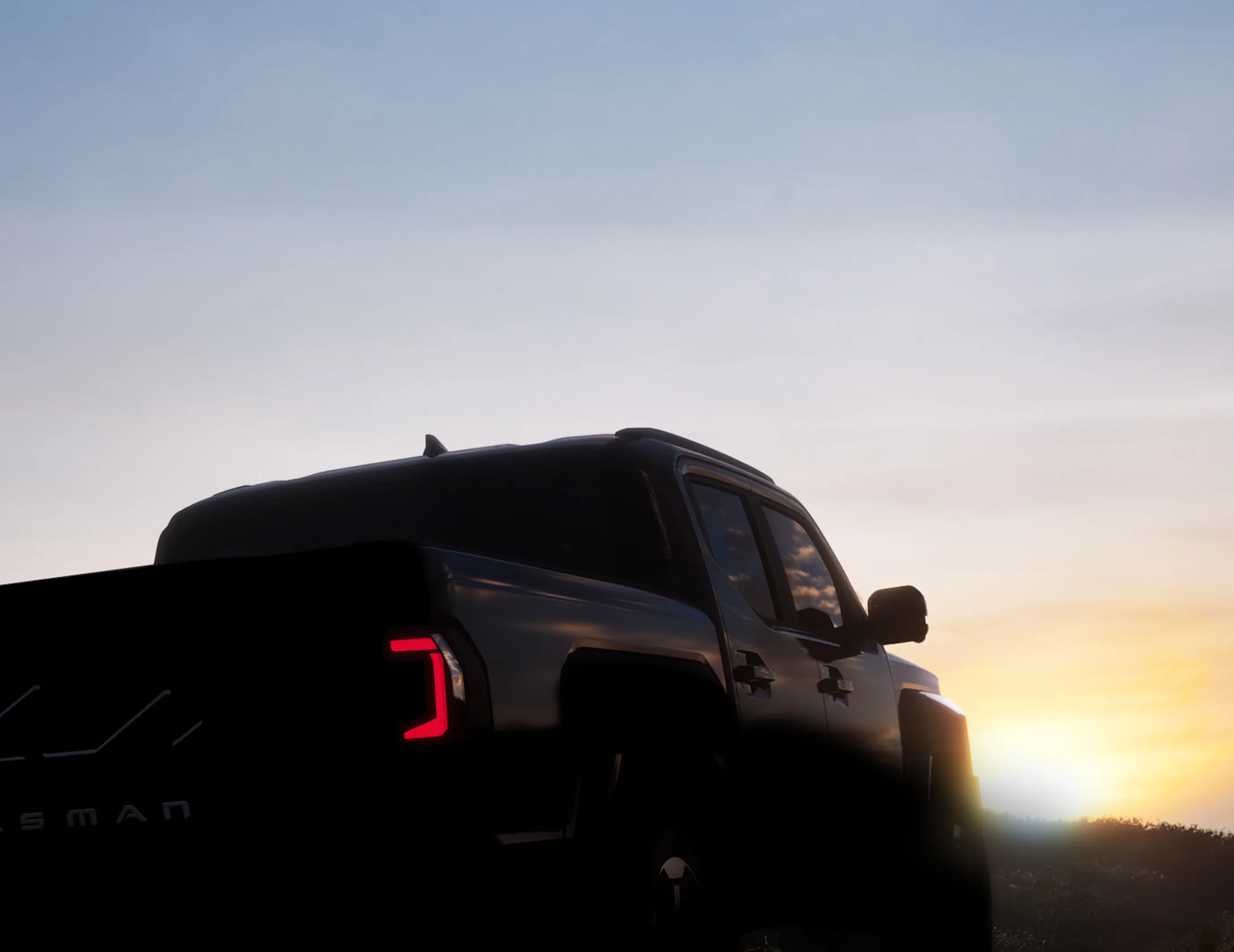 Rear silhouette view of the Kia Tasman pickup truck at dusk