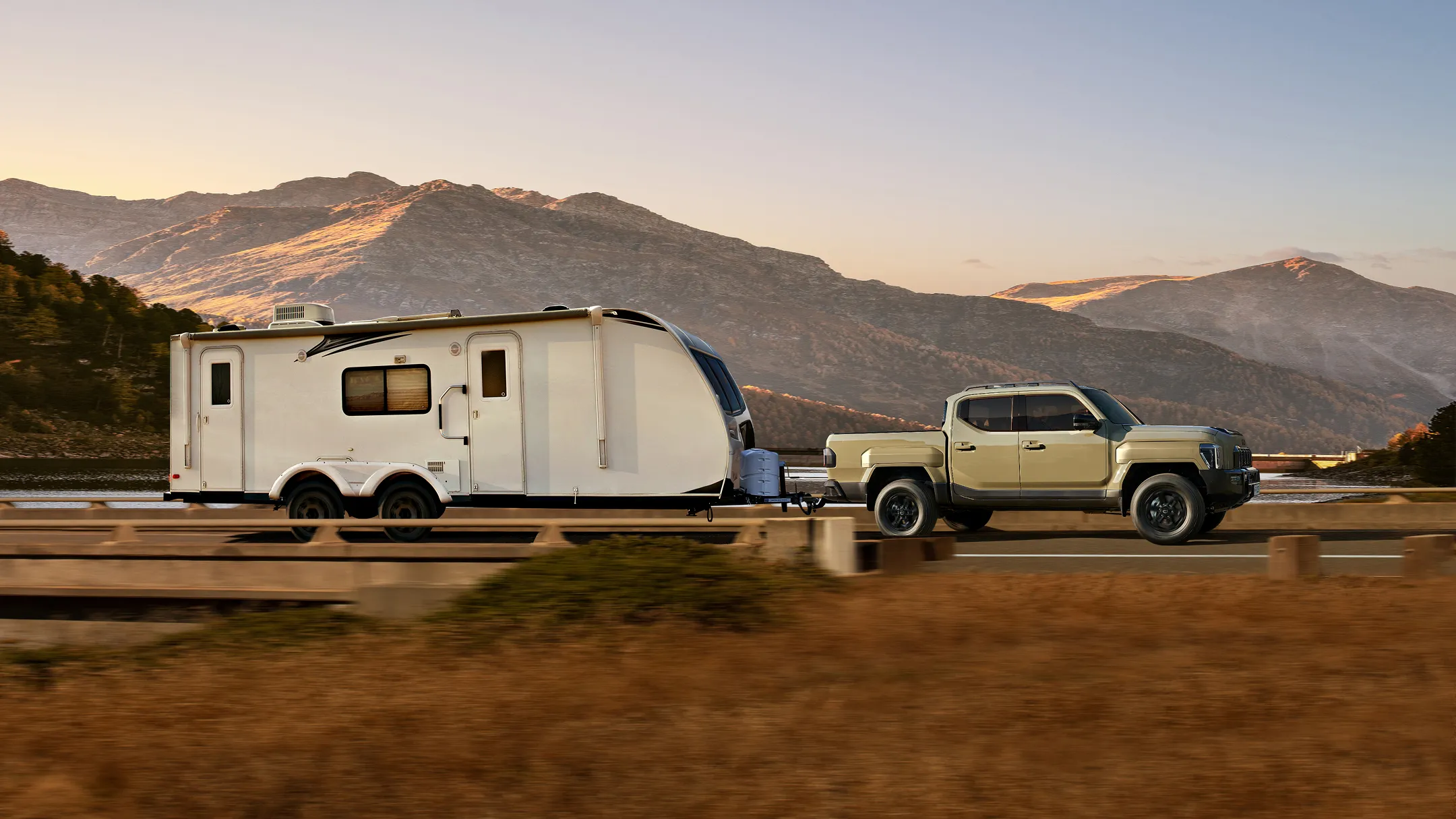 The Kia Tasman pickup truck towing a trailer while driving through a natural landscape