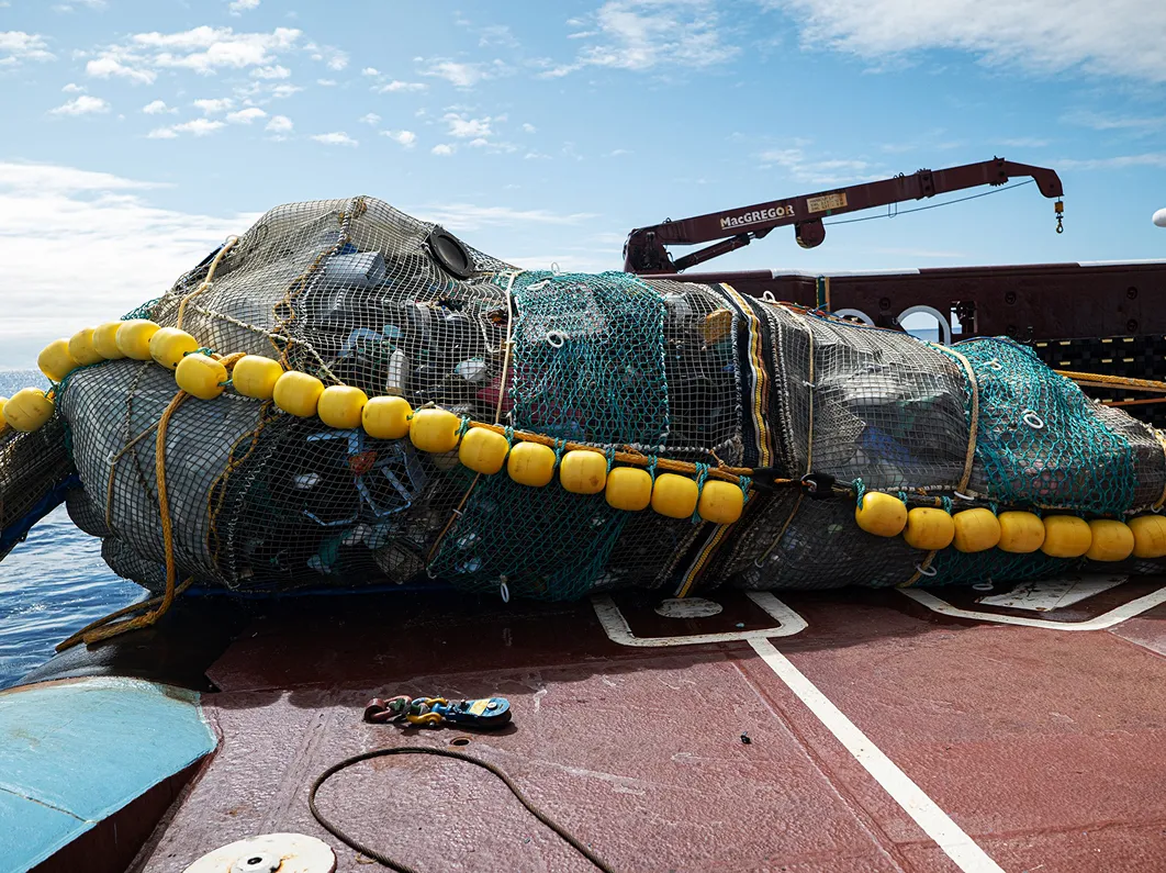 Large marine waste collection nets and buoy equipment loaded on a ship deck at sea