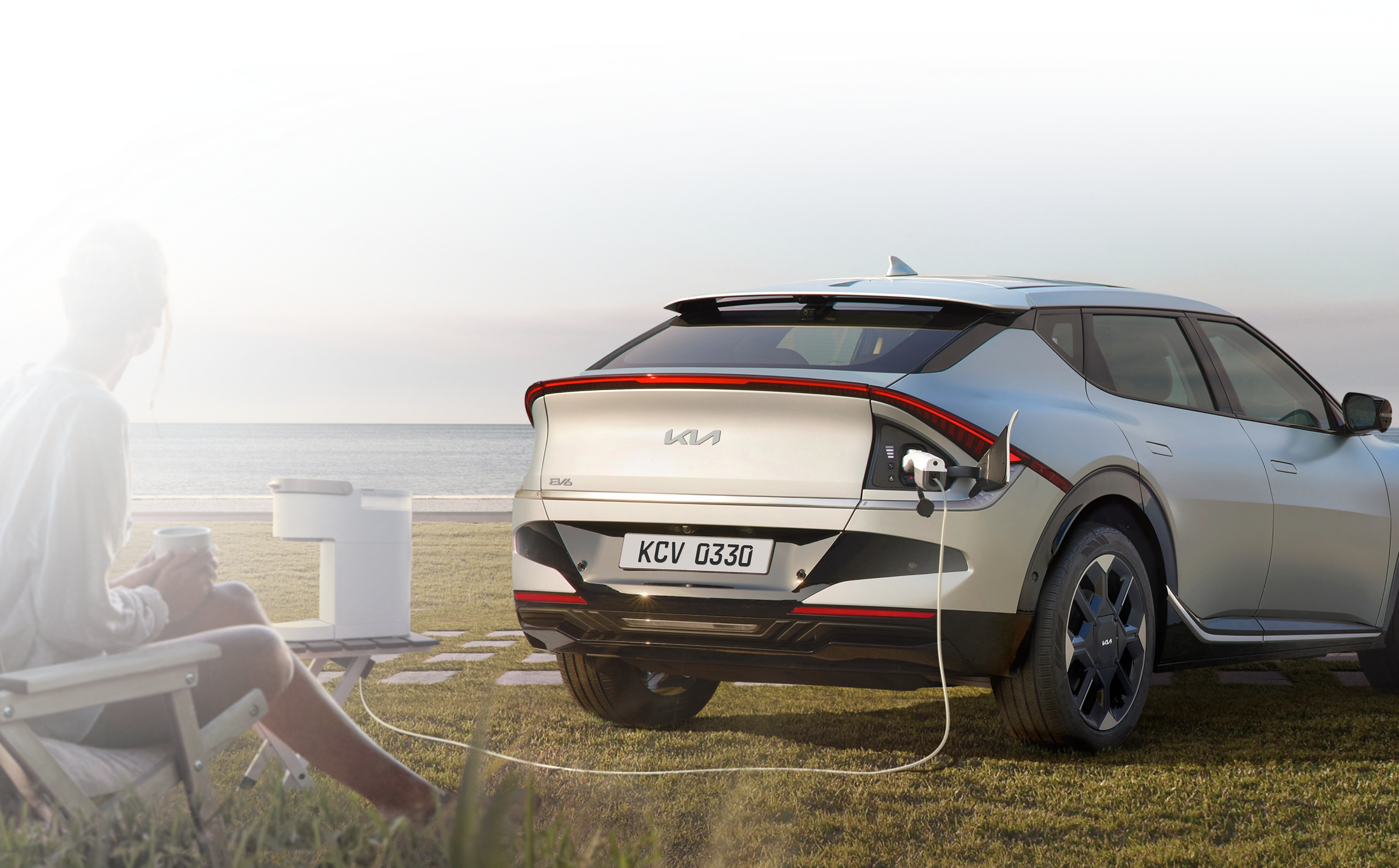 Rear three-quarter view image of the Kia EV6 charging via V2L outdoors