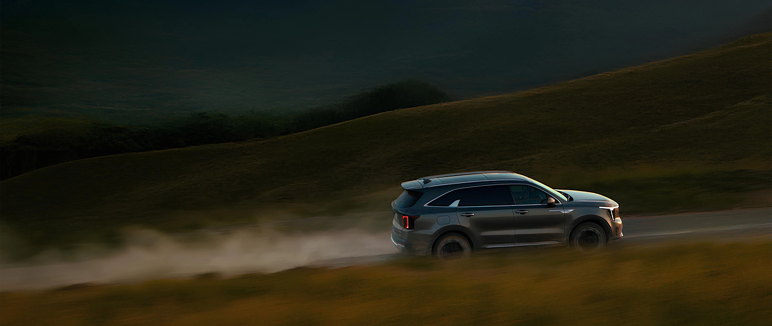Image of a Kia SUV driving through a natural landscape