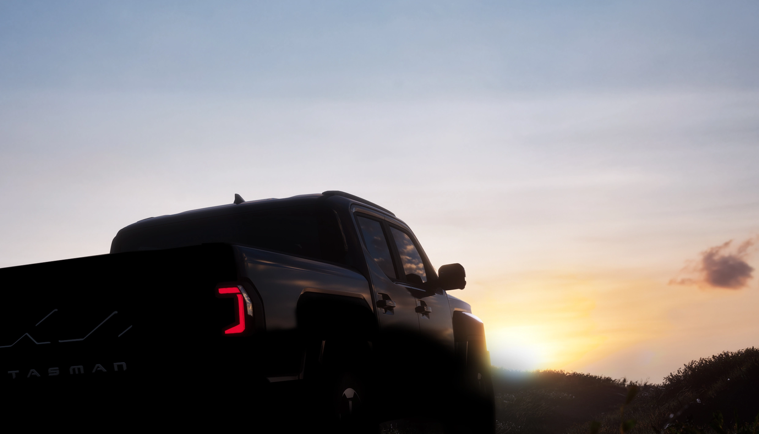 Rear silhouette view of the Kia Tasman pickup truck at dusk